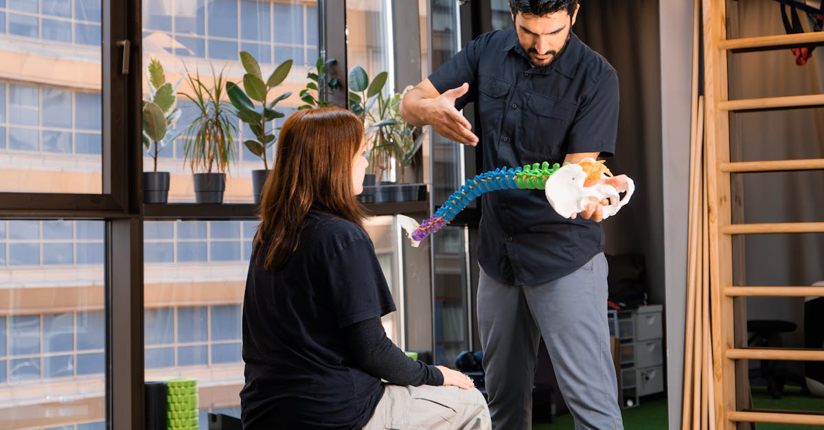 Chiropractor demonstrating spine anatomy to a patient during consultation indoors.